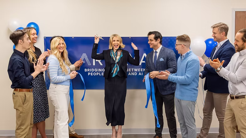 Arvaya founder cutting a blue ribbon in front of the Arvaya banner as team members applaud at the Charleston office opening