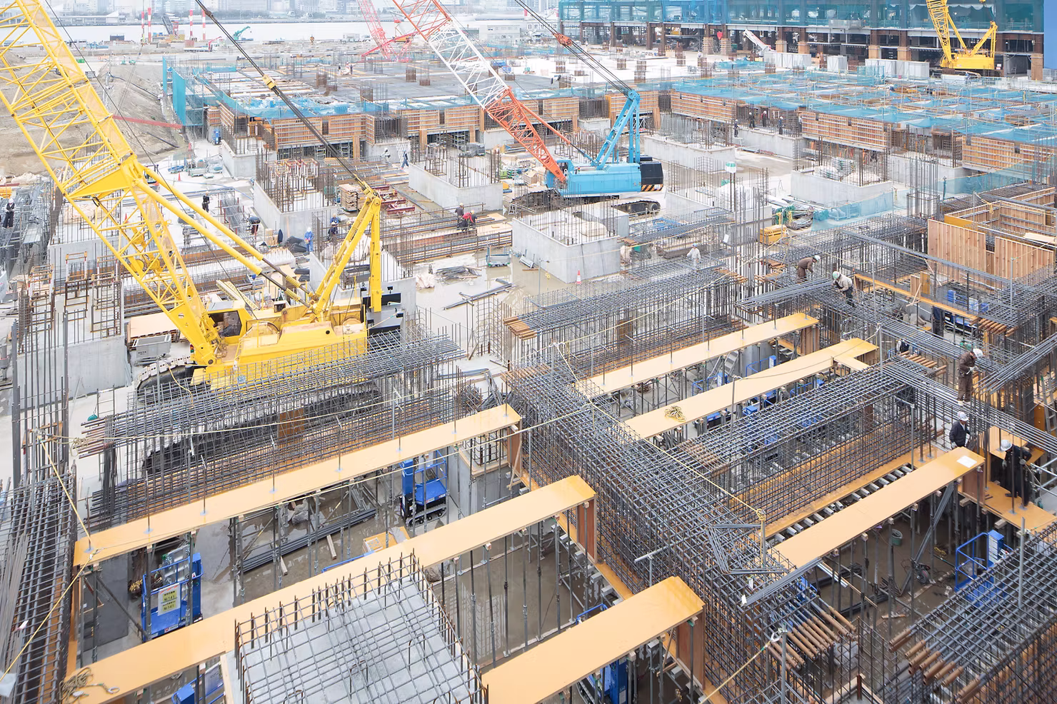 Aerial view of a large construction site with crawler cranes, rebar cages, and formwork as crews build a concrete foundation